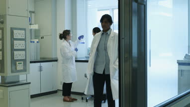 Two female scientists discussing results of experiment in busy laboratory