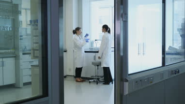 Two female scientists discussing results of experiment in busy laboratory