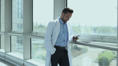 Male medical professional using smartphone in corridor