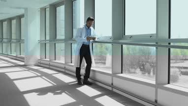 Male medical professional using smartphone in corridor