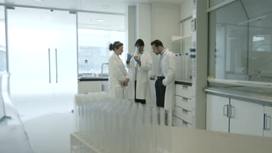 Team of scientists discussing liquid experiment 