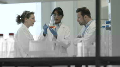 Team of scientists discussing liquid experiment 