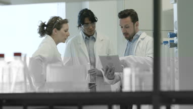 Team of scientists discussing experiment data on digital tablet