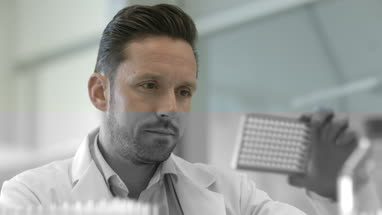 Male scientist looking at microplate in a laboratory