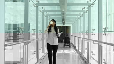 Female business executive walking through busy office corridor