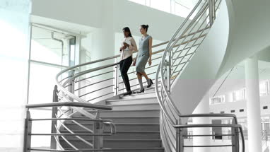Female business colleagues walking down spiral staircase