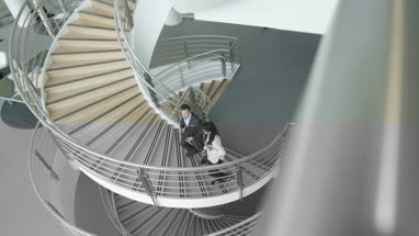 Overhead business colleagues walking up spiral staircase discussing work