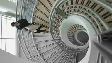 Overhead business colleagues walking down spiral staircase discussing work