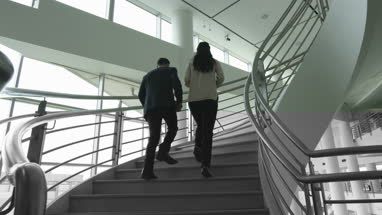 Businessman walking up spiral staircase in office