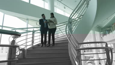 Business colleagues walking down spiral staircase