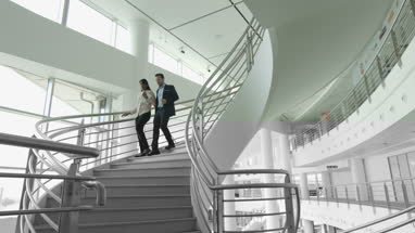 Business colleagues walking down spiral staircase