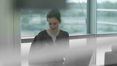 Female executive syncing smartphone to laptop