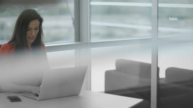 Female executive syncing smartphone to laptop