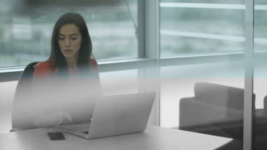 Female executive working on laptop and using smartphone