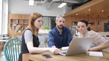 Coworkers looking at a laptop in a meeting