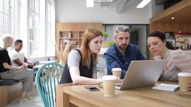 Coworkers looking at a laptop in a meeting