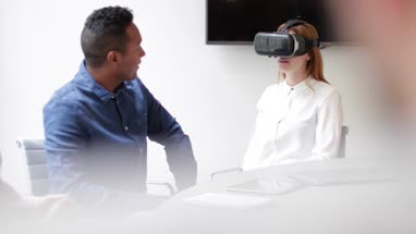Designer trialing a virtual reality headset in a meeting