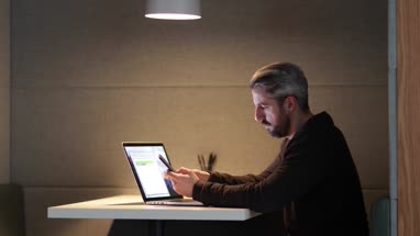Businessman working late at night in office using smartphone