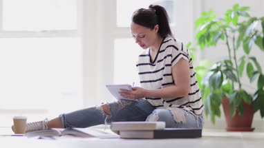 Female designer working on ideas with digital tablet and paperwork on office floor