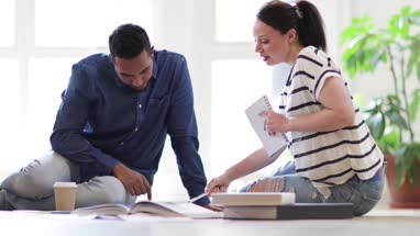Colleagues working on ideas with digital tablet and paperwork on office floor