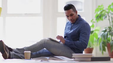 Male designer working on ideas with digital tablet and paperwork on office floor