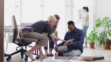 Colleagues discussing ideas with paperwork on office floor