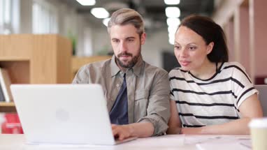 Coworkers looking at a laptop together