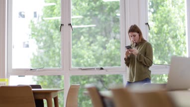 Businesswoman in empty office looking at smartphone