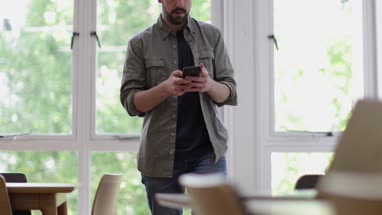 Businessman in office using smartphone and laptop