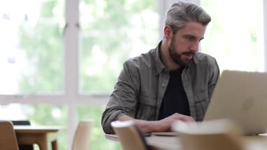 Businessman in office using smartphone and laptop