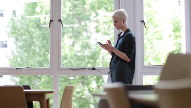 Businesswoman in empty office looking at smartphone