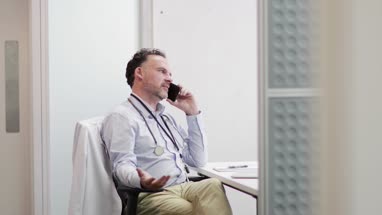 Stressed Medical Doctor on phone in his office