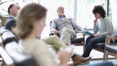 Senior Male waiting in a crowded hospital waiting room 