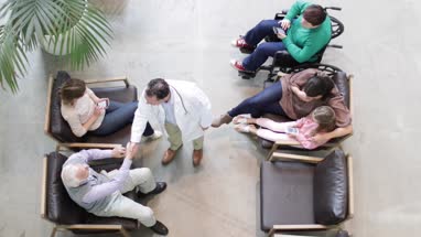 Overhead shot of Medical Doctor greeting Senior Male in waiting room
