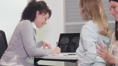 Female medical Doctor writing a prescription for a child