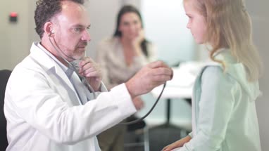 Male Medical Doctor listening to child's heartbeat