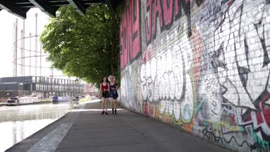 Female friends walking by canal in urban city