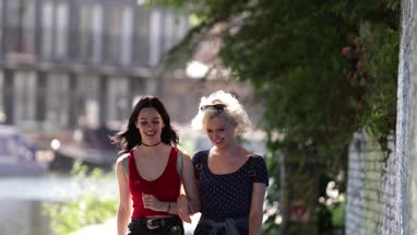 Female friends walking by canal in urban city