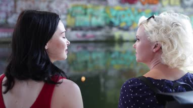 Female friends relaxing by canal in urban city
