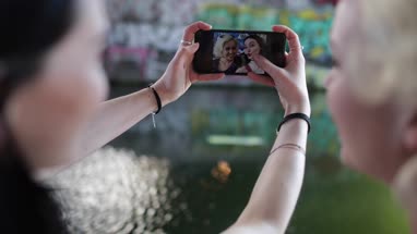 POV female friends reviewing selfies in urban city