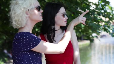 Female friends enjoying sun in urban city by canal