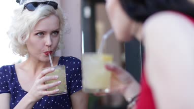 Female friends enjoying a refreshing drink outdoors in summer