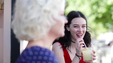 Female friends enjoying a refreshing drink outdoors in summer
