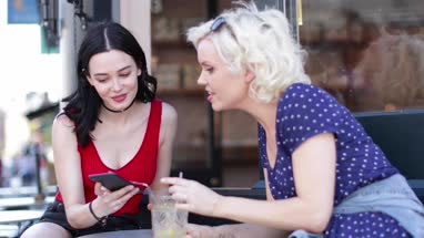 Female friends at a bar looking at smartphone
