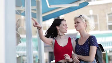 Female friends walking down a street of shops in summer