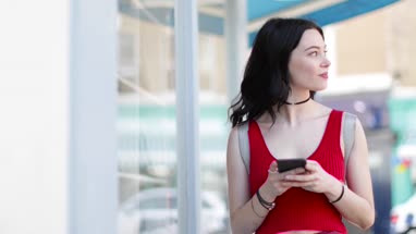 Young adult female walking down street whilst on smartphone