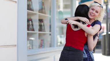 Female friends meeting outdoors on shopping street