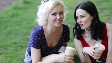 Female friends having takeout coffee in the park