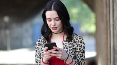 Young adult female using smartphone on street