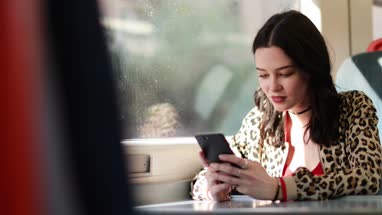 Young adult female travelling on train looking at smartphone